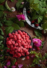 Fresh juicy raspberries on a black plate.