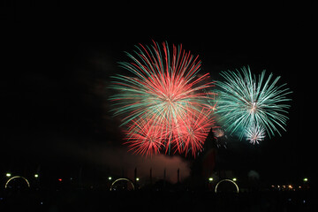 Fototapeta na wymiar Multicolored fireworks in the dark sky, city day celebration.
