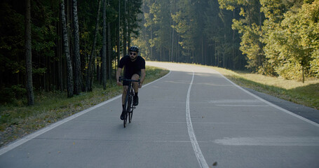 Obraz premium Cyclist riding his bicycle on an empty forest road