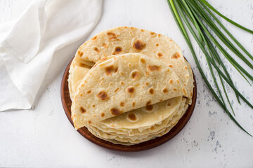 Traditional Tatar flatbread, kastyby and a bunch of green onions on a light gray background, top view