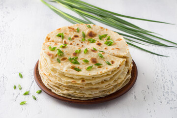 Traditional Tatar flatbread, kastyby and a bunch of green onions on a light gray background