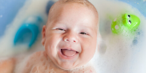 Baby bath time. Close-up detail view of mother bathing cute happy smiling baby in tub with water...