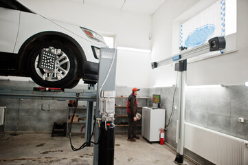 American SUV car on stand for wheels alignment camber check in workshop of service station. - obrazy, fototapety, plakaty