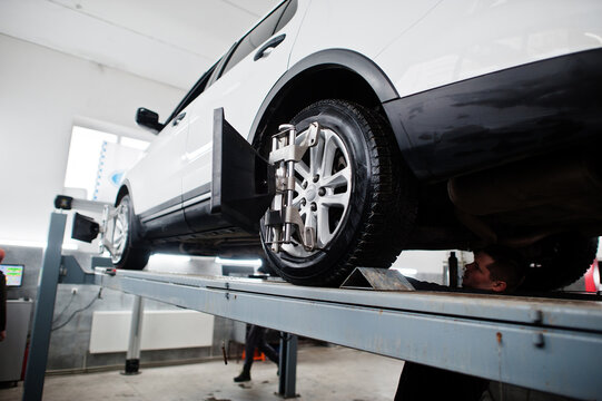 American SUV car on stand for wheels alignment camber check in workshop of service station.