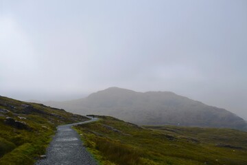 Beautiful misty road on the green hillside in the highlands