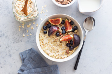 Oatmeal porridge with figs, blueberries, almonds and honey. Healthy eating. Vegetarian food. Breakfast. - obrazy, fototapety, plakaty