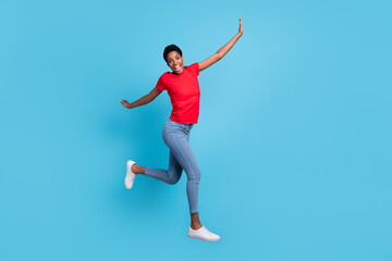 Fototapeta na wymiar Photo of excited good mood short hair human wear red t-shirt jumping high running fast isolated blue color background