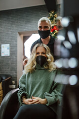 Fototapeta premium Beautiful hairstyle of woman after dyeing hair and making highlights in hair salon. She is wearing protective face mask as protection against virus pandemic.