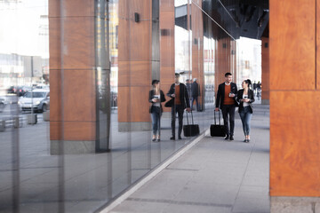 Fototapeta na wymiar Business man and woman walking and drinking coffee. Businesspeople traveling together with luggage.