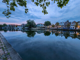 Houses on the Spaarne River in Haarlem, Netherlands, with the last light of day and reflections on the water. 