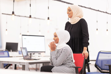 Two african american muslim girls with hijab applauding. Colleagues cheering together in a modern...