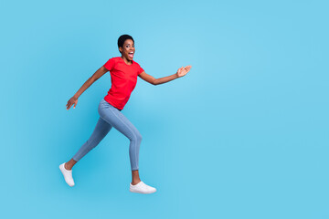 Fototapeta na wymiar Photo of cheerful positive short hair person dressed red t-shirt running fast jumping high isolated blue color background