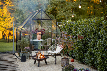 Beautiful and cozy garden with a picnic fire at lounge area and vintage greenhouse behind. Atmospheric and very beautiful courtyard of a country house