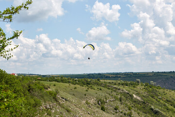 Ukraine flag paraglider flying midday over canyon in Butuceni, Moldova
