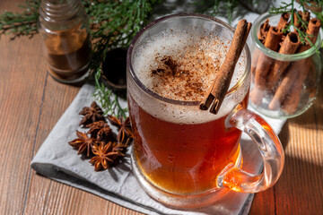 Autumn spiced mulled beer. Hot dark beer with spices - vanilla, cinnamon, anise, citrus, hot homemade alcohol drink, with small pumpkins on wooden kitchen table