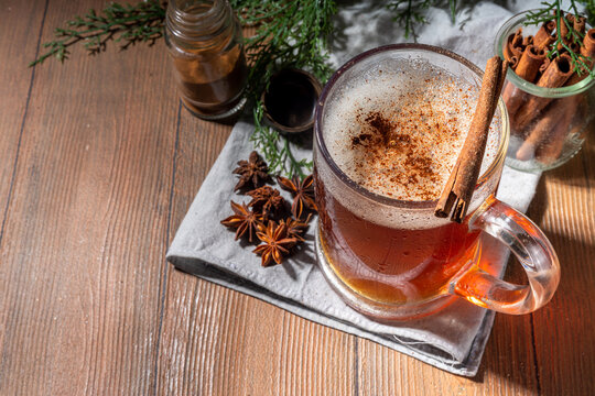 Autumn spiced mulled beer. Hot dark beer with spices - vanilla, cinnamon, anise, citrus, hot homemade alcohol drink, with small pumpkins on wooden kitchen table