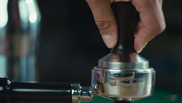 Close-up of a barista's hand tamping coffee into a cone. Slow motion video of coffee ready to be brewed. High quality 4k footage