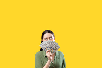 Stock market and exchange. Portrait of Caucasian woman covering face with fan of dollar currency and looking up. Copy space. The concept of shopping, income and banking