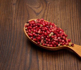 Red peppercorns in a wooden spoon on the table, spice