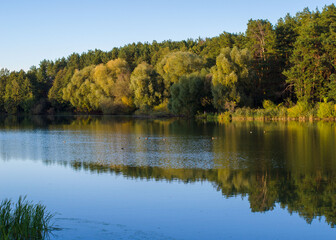 Beautiful autumn landscape. Pine and deciduous forest, clear lake and blue sky. Autumn in Chernigov, Ukraine