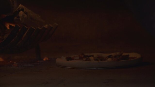 The professional chef bakes traditional Capricciosa pizza in a high-temperature metal woodfired pizza oven. Pizzaiolo cooks a traditional Italian dinner in a modern restaurant kitchen with his hands.