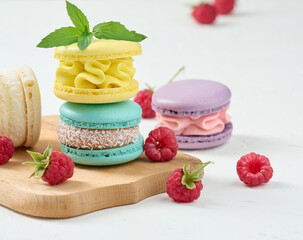 Obraz na płótnie Canvas Stack of multicolored macaroons and red raspberries on a white background.