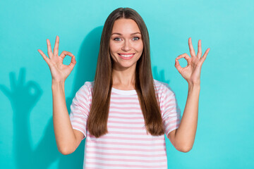 Photo of good mood optimistic girl with long hairstyle wear striped t-shirt showing okey symbol isolated on turquoise color background