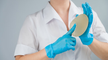 A plastic surgeon shows a breast silicone implant.