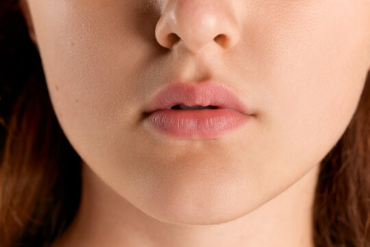 Cropped image of plump female lips. Nude makeup. Smooth skin. Cosmetological face care