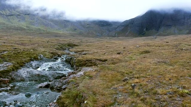 Exploring shot of the Fairy Pools with fog covering the large mountains in the Highlands