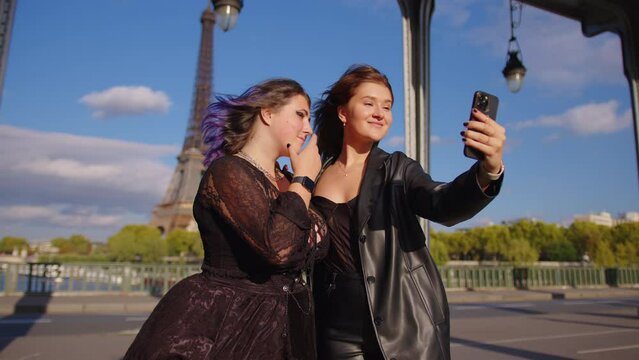 Two girls take a selfie on their phone in the most visited city in the world. Traveling together concept. A young couple takes a photo in Paris. Video phone call