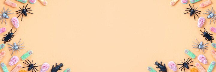 Halloween sweet background frame with scary pumpkin cookies, candy and Halloween decor on orange table