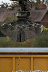 A digger grab moving stone on the railway
