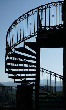 spiral Steel Staircase. Blue sky and metal spiral staircase on mountain background.