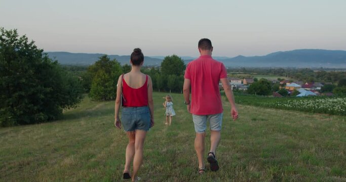 Family, mom, dad and little girl went for a walk in nature on a evening or morning meadow during quarantine. Time spent with family