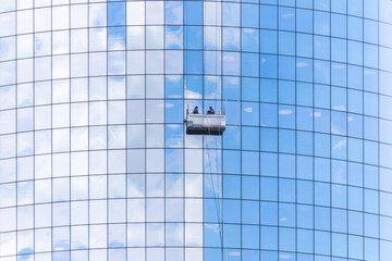 Two cleaners washing the windows of modern skyscraper