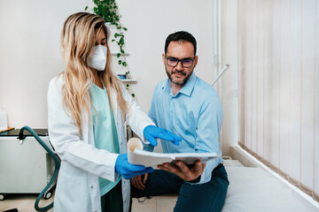 Middle age man sitting and talking with doctor at medical clinic for the treatment of infertility...