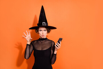Photo of attractive terrifying lady hold telephone arm make scary boo gesture isolated on orange...