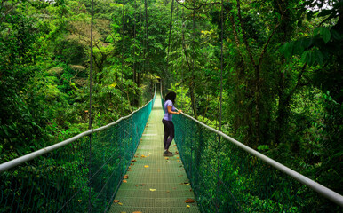 Young girl on suspension bridge with forest background in Central America