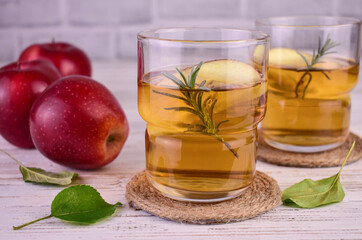 Two glasses of apple juice with cinnamon on a white background.
