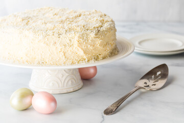A creamy white frosted coconut covered cake for Easter, ready for serving.