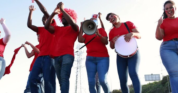 Latin red sport fans screaming while supporting their team - Football supporters having fun at competion event - Champions and winning concept
