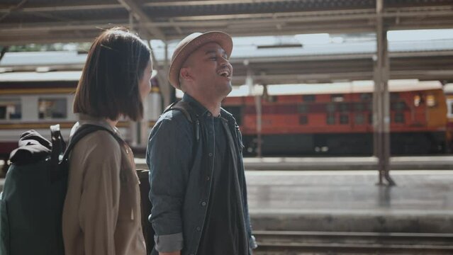 	
Happy asian handsome man and beautiful woman backpacker wearing hat and backpack walking and talking together in the train station going to travel. 4k resolution.