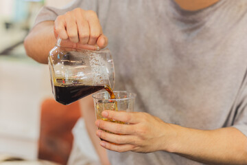 Barista pouring coffee into takeaway glasses in the coffee shop.