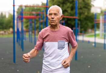 Obraz premium Active senior man is jogging in summer park. Healthy retirement lifestyle