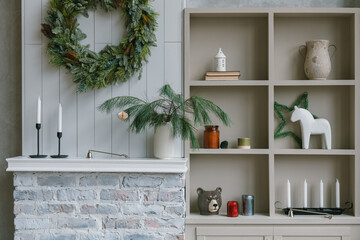 Dresser, fire place, wreath, a vase with fir branches. Festive holiday background. Cozy home interior decorated for Christmas holidays. 