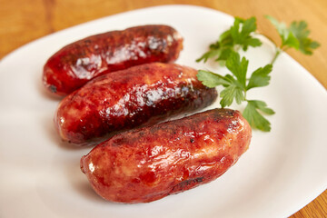 Fried sausages on a white plate.