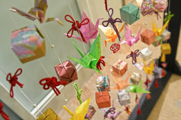 Japanese art installation made of paper cranes, ribbons and boxes.