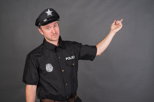 Portrait of Caucasian man wearing police uniform costume pointing finger to copy space