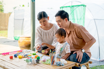 Asian family with father mother and son enjoy to have good activity together to paint eggs relate...